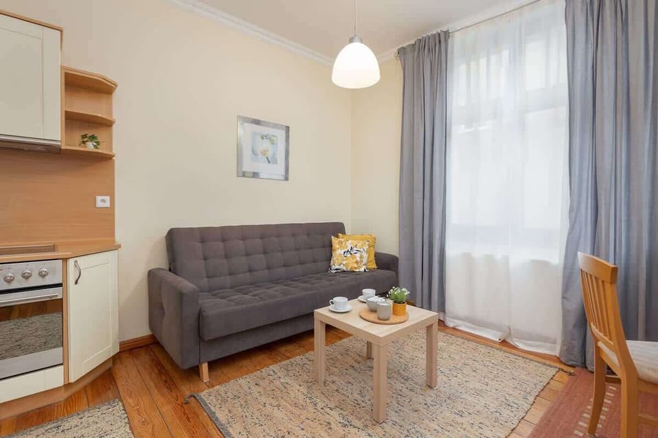 A bright and spacious area featuring a large window, an elegant dining table with chairs, and a comfortable sofa.