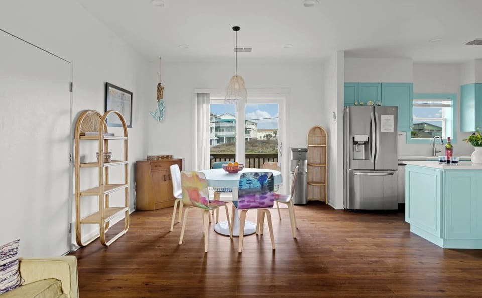 Dining Area — Round Table with Colorful Watercolor Chairs & Turquoise Kitchen