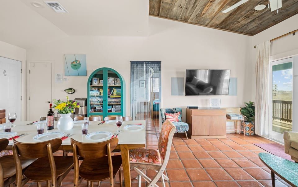 Dining & Living — White Table, Wine, Teal Game Cabinet, Board Games, Wall TV & Reclaimed Wood Ceiling