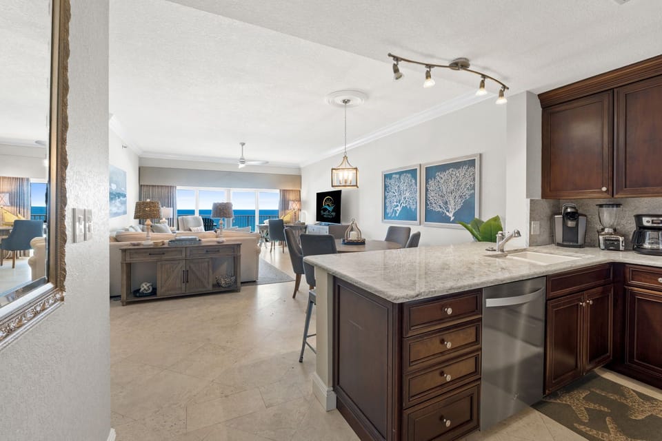 Open-concept kitchen flows into dining and living with beach backdrop.