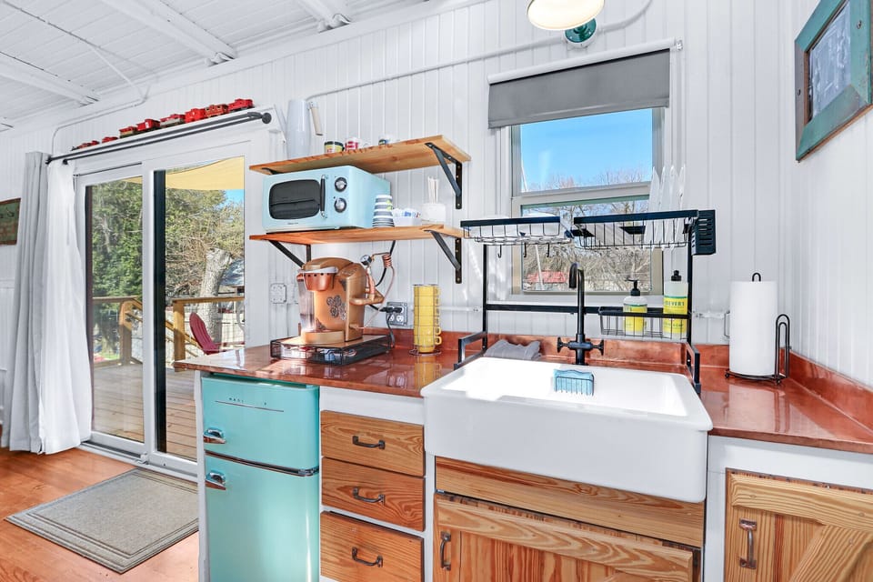 The kitchenette features a large farmhouse style sink, a mini fridge, and a little microwave