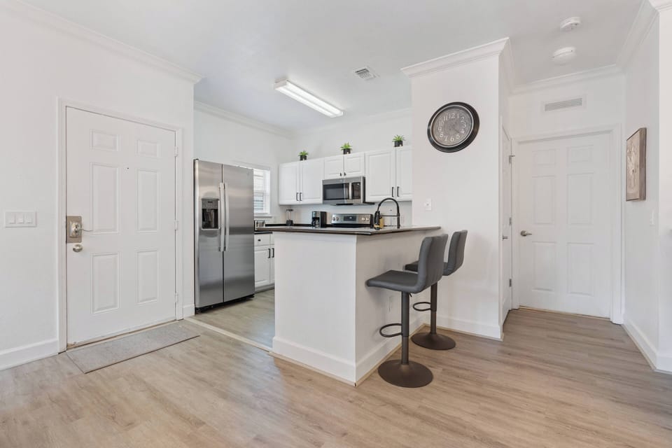 Welcome to a bright kitchen with stainless steel appliances and a spacious island for casual dining. The light wood flooring and crisp white cabinetry create a clean, inviting space that's perfect for your culinary adventures.