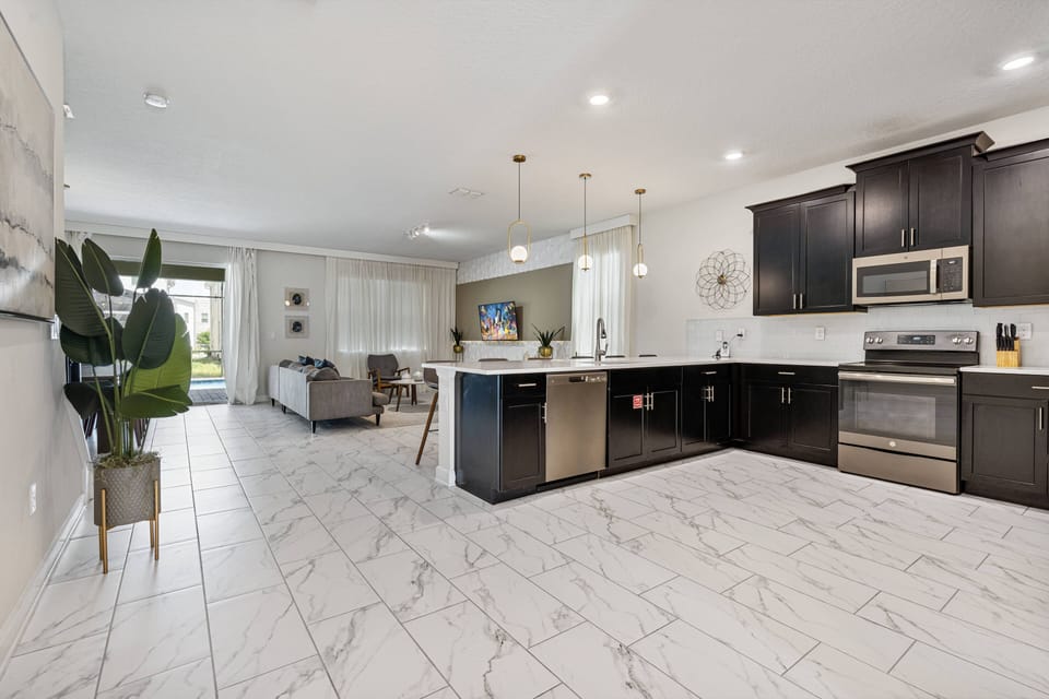 Enjoy cooking in this bright, spacious kitchen with sleek dark cabinetry and a stunning marble-patterned floor. It’s a stylish and functional space, equipped with modern appliances and plenty of counter space for your culinary.