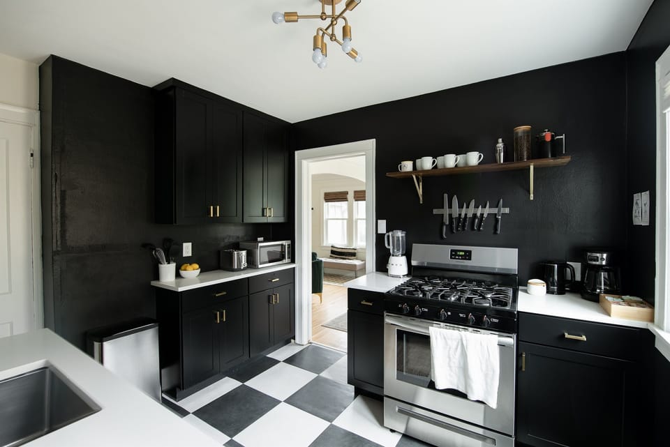 Newly renovated black and white kitchen with custom cabinets, antique brass fixtures, new stainless steel oven, sharp knives, and a full coffee / tea setup.