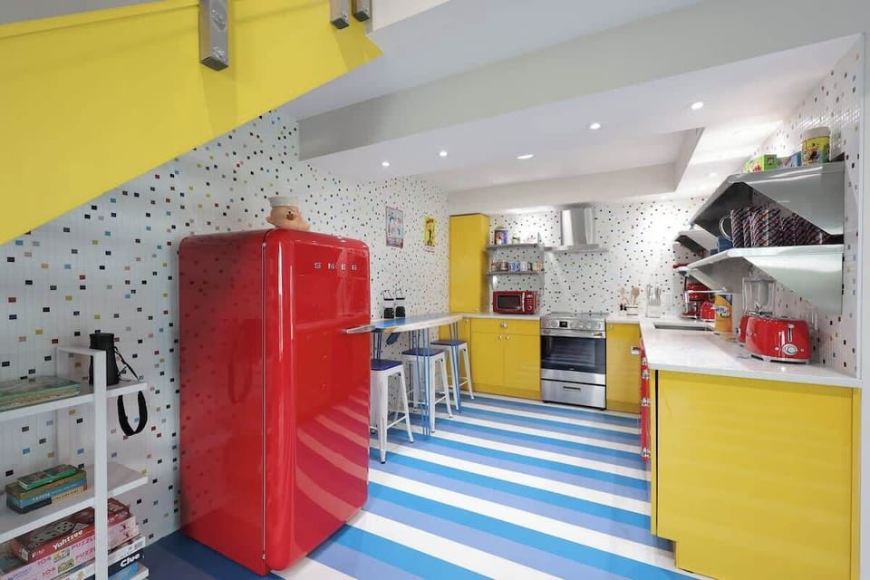 Fun surfboard dining table for four, set in a bright retro kitchen with striped floors.