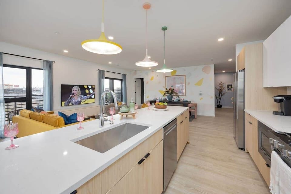 Fully equipped kitchen stocked with all culinary essentials and featuring brand-new stainless-steel appliances and a large kitchen island offering bar seating.