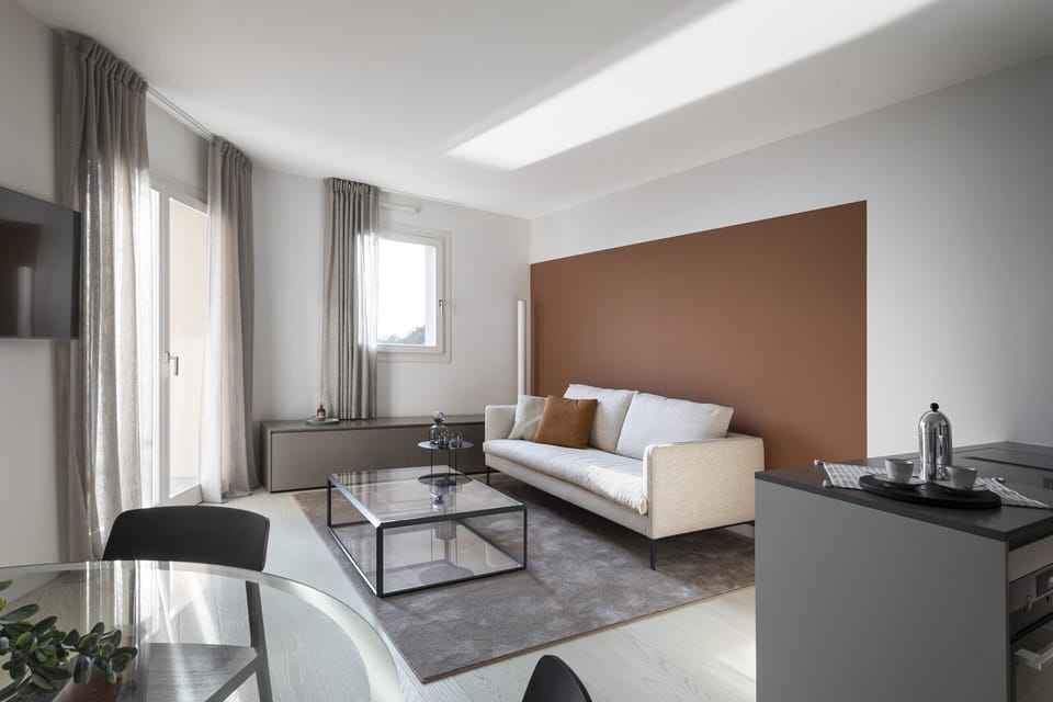 Luxurious living room at Portopiccolo Apartments - Pearl in the Village. Ideal for couples, families, and business trips. A luxury apartment, fully equipped and furnished with every comfort. Characterized by a breathtaking sea view. Featuring two bedrooms and two bathrooms with showers, accommodating up to four people. It comes with a fully equipped kitchen and indoor and outdoor dining areas. The apartment is complemented by WiFi and reserved covered parking.