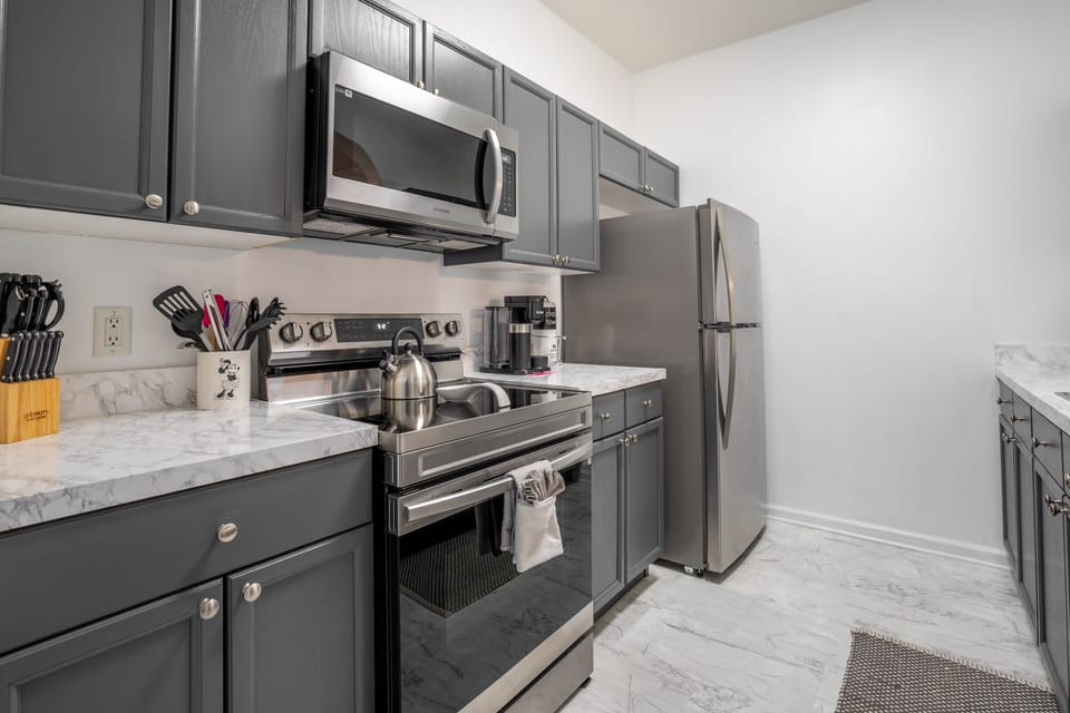 Modern kitchen featuring stainless steel appliances and gray cabinetry with marble countertops.