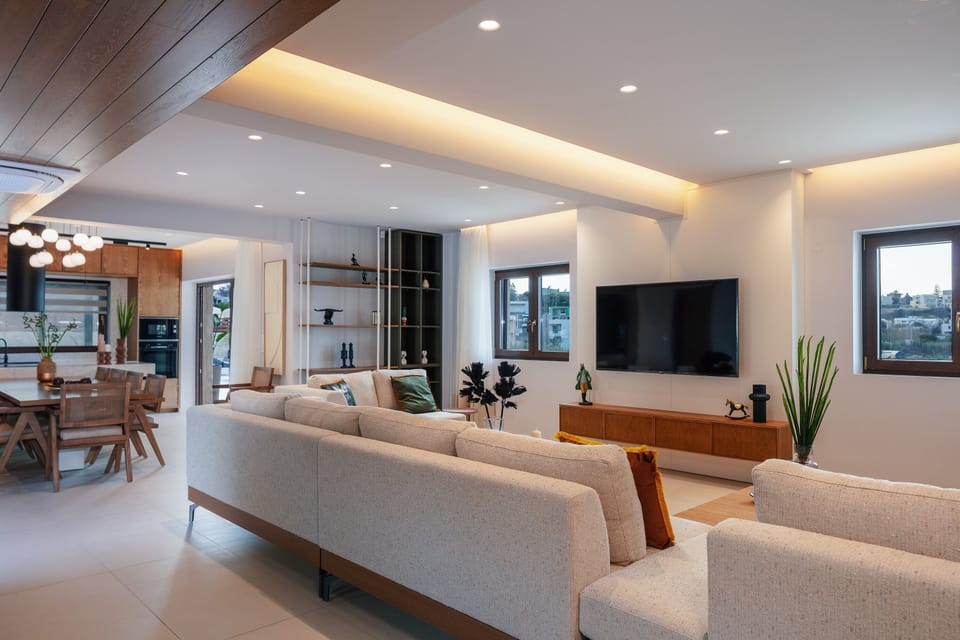 Spacious open-plan living room area with a large sofa, 65” Smart TV, and direct access to the pool area.
