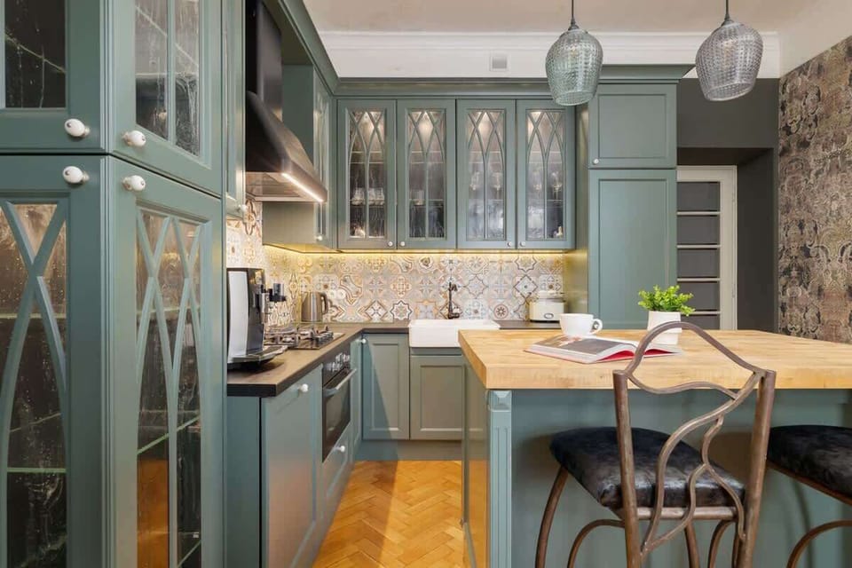 A practical kitchen with green cabinets, wooden worktops and elegant glass doors. 