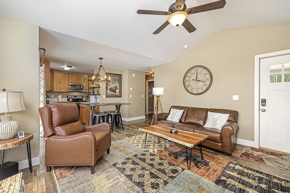 Living area with a sofa, two chairs, flat screen TV and ceiling fan