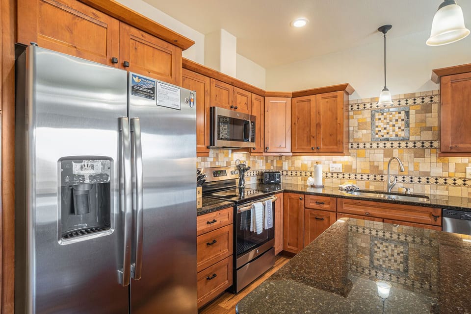 Open kitchen with large refrigerator with ice maker, glass top stove/oven and microwave. 