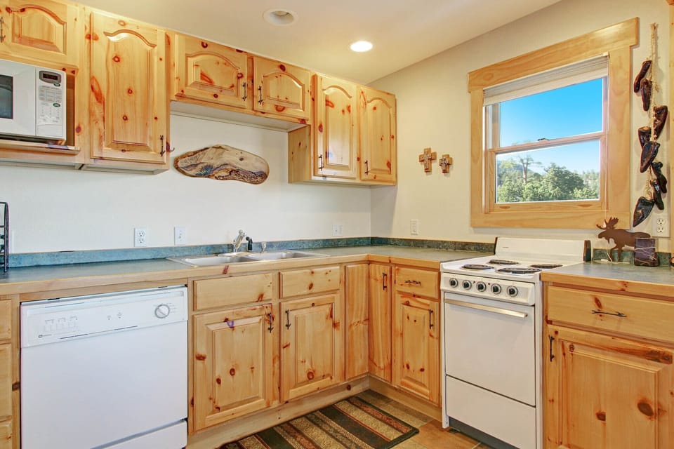 Beautiful log cabinets in kitchen. White oven, stovetop, dishwasher, and microwave.