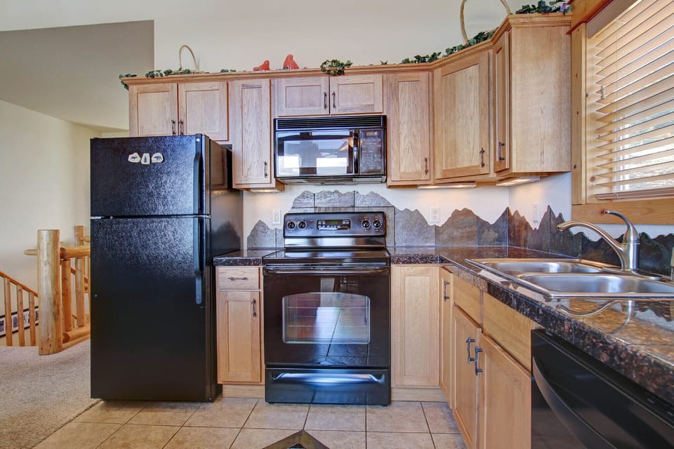 Beautifully decorated full kitchen. Mountain-themed granite backsplash along countertops. Full size refrigerator, dishwasher, oven, stovetop, and microwave.