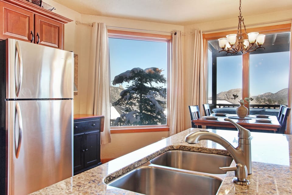 Full size refrigerator and double sink in kitchen with dining area that seats 6 with views out the large windows. 