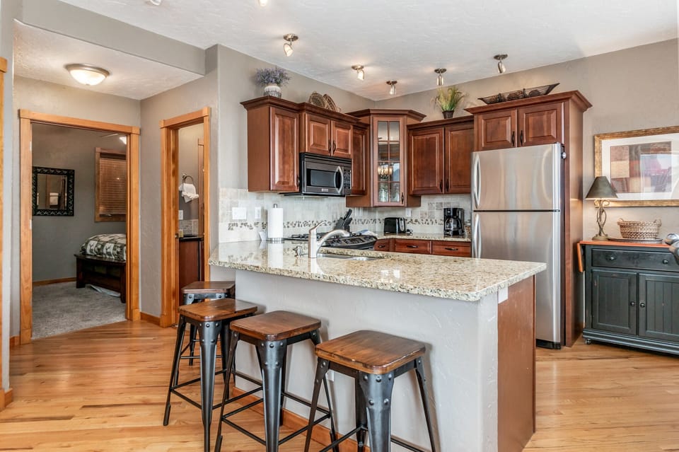 The open concept living area and bar seating with 4 stools and kitchen with full refrigerator, microwave, gas stove, toaster and coffee maker. 