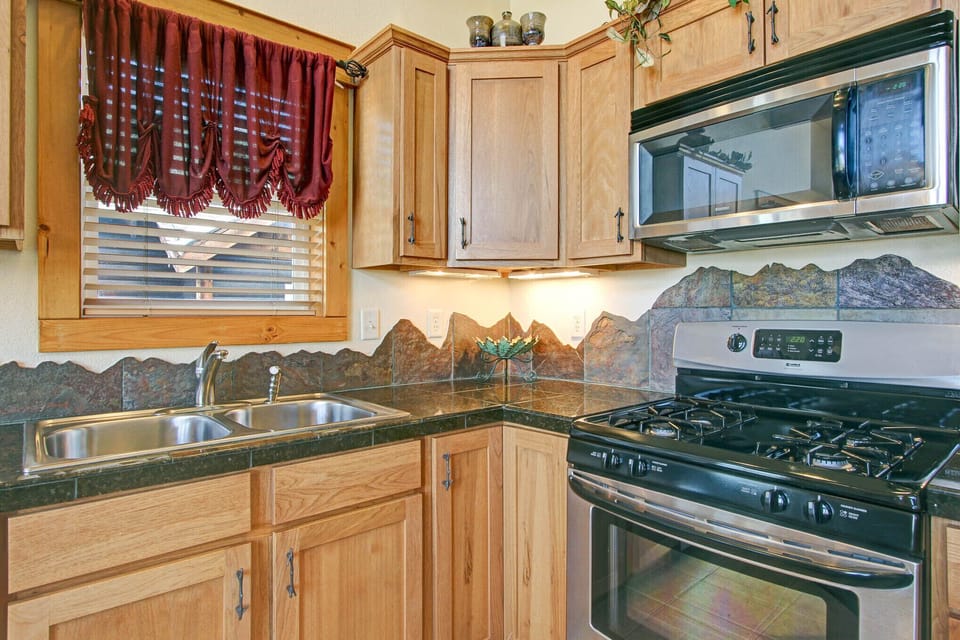 Beautifully decorated full kitchen. Mountain-themed granite backsplash along countertops. Full size refrigerator, dishwasher, gas stove/oven and microwave.