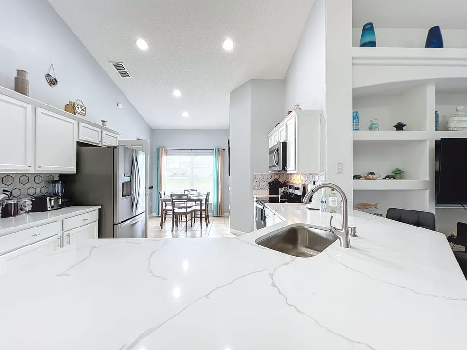 - Sleek white countertops & modern appliances create a bright, polished kitchen
- Open concept layout keeps the conversation flowing from kitchen to living space
- Natural light pours in from the dining area, making every meal feel fresh & inviting