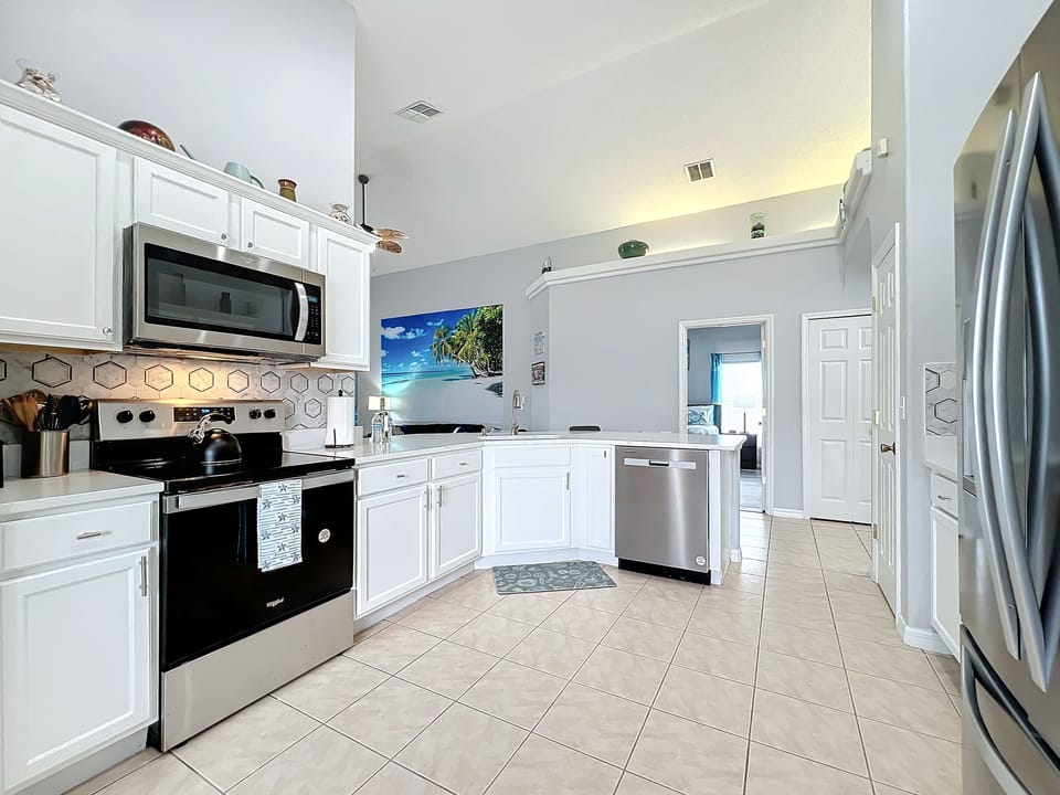 - Sleek white cabinetry and stainless steel appliances create a clean, coastal look
- Fully stocked with cookware and utensils for whipping up family meals with ease
- Tropical wall art and light tile flooring complete the bright, breezy vibe