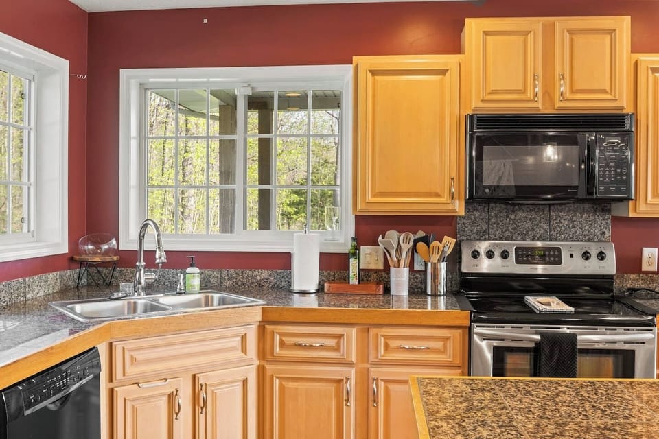 Craft your favorite dishes in this beautifully appointed kitchen with sleek appliances and rich wooden cabinetry, complemented by a charming view from the window.