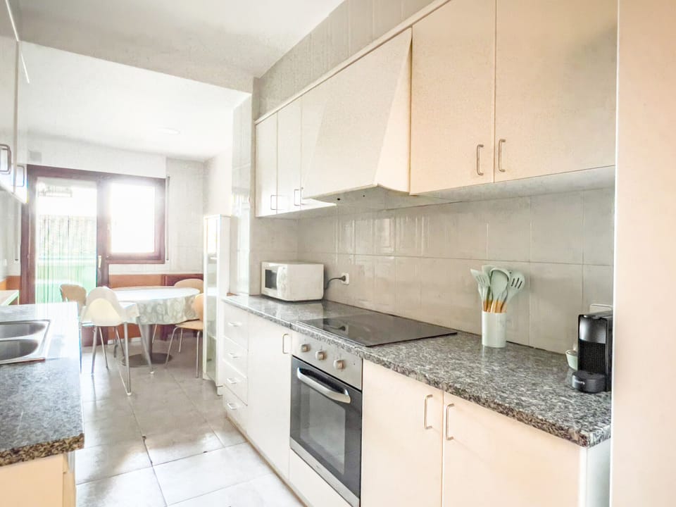 This bright and spacious kitchen in a Banyoles apartment offers a functional design with modern appliances, ample storage, and a cozy dining area. Large windows provide plenty of natural light, making it a perfect space for cooking and enjoying meals.