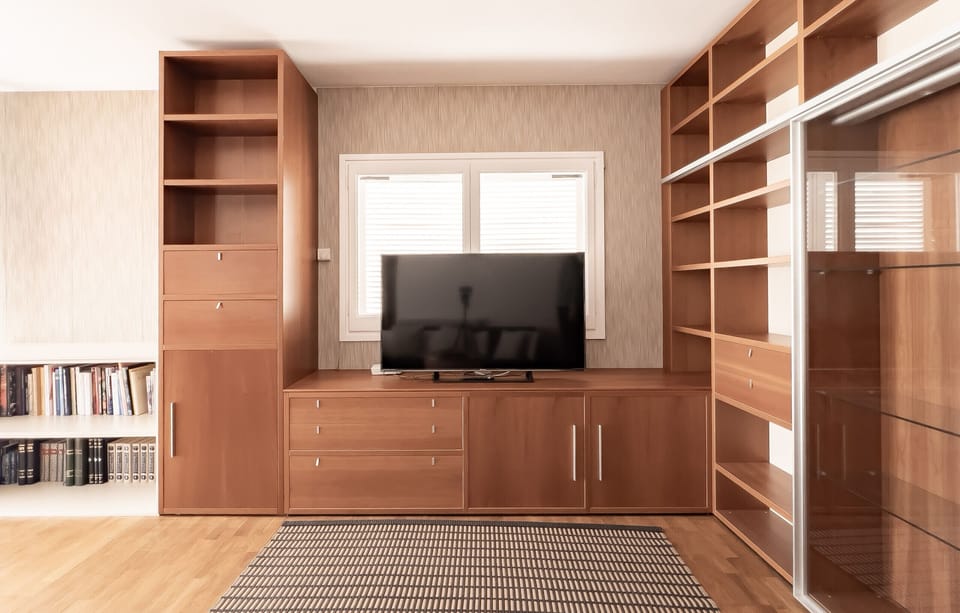 A stylish living space in Banyoles featuring built-in wooden shelves, a large TV, and a cozy reading nook.