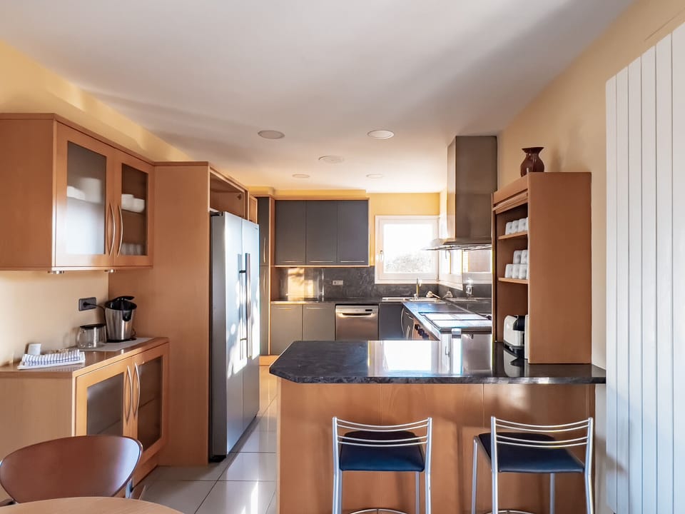 A bright and spacious modern kitchen featuring a breakfast bar, sleek cabinetry, and high-end appliances. Designed for comfort and functionality, ideal for preparing meals and socializing.