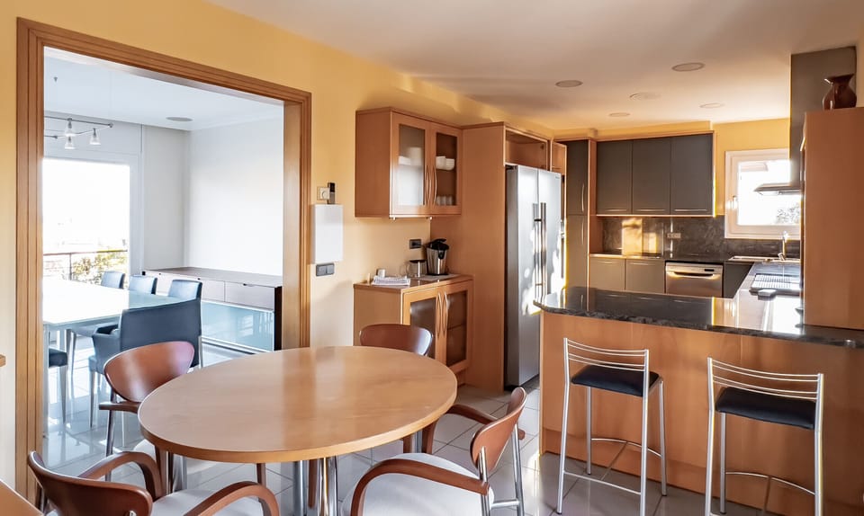 A bright and spacious modern kitchen featuring a breakfast bar, sleek cabinetry, and high-end appliances. Designed for comfort and functionality, ideal for preparing meals and socializing.