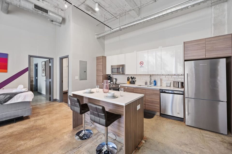 Cozy apartment in Dallas with kitchen island, industrial accents & colorful art—modern retreat blending function and style.
