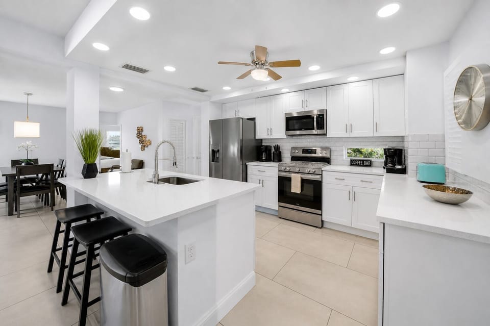 Fully equipped kitchen featuring stainless steel appliances, large island, and open dining flow.