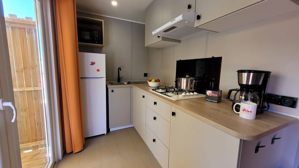 The modern kitchen is equipped with essential appliances including a stove, refrigerator, and coffee maker, featuring a warm and inviting design.
