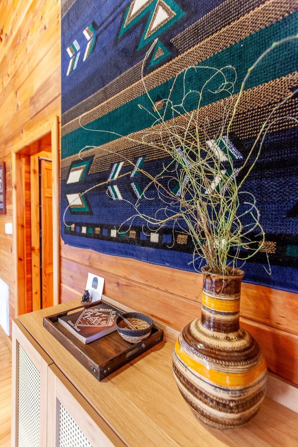 Log cabin hallway featuring wood-paneled walls, decorative textile artwork, and rustic accents at Dream Circle Cabin. Warm natural finishes create a cozy mountain retreat atmosphere near Bryson City.