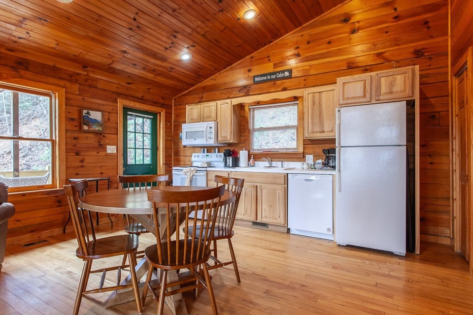 Dining table for four and a fully equipped kitchen are featured in the open-concept gathering space. This Bryson City cabin offers a functional layout for meals and relaxing in the Smoky Mountains.
