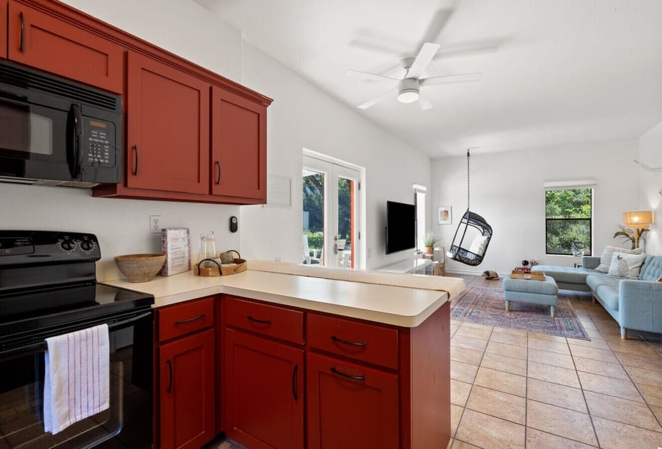 Warm, open kitchen and living space with rustic red cabinetry and cozy charm