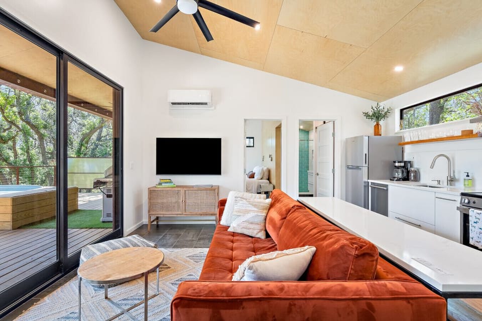Warm, modern living space with a cozy sofa and full glass doors to the deck