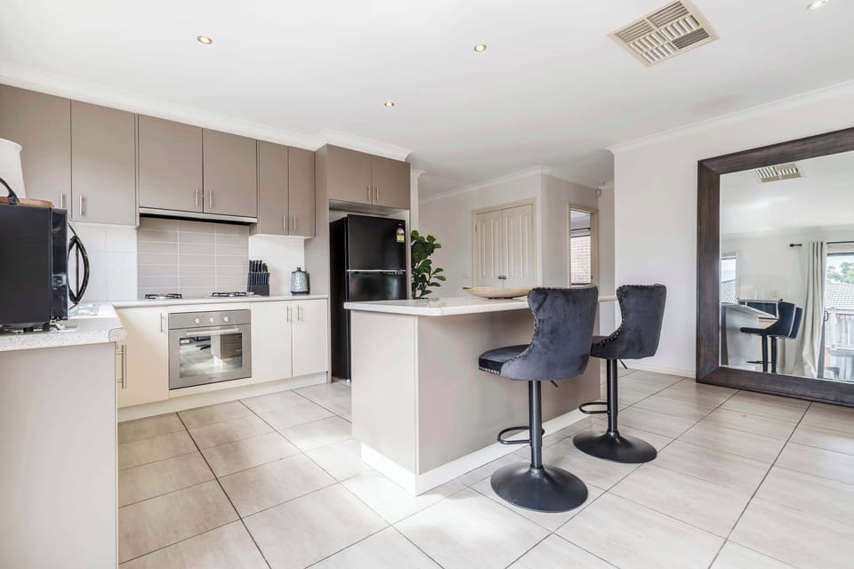 KITCHEN: Enjoy cooking in a fully equipped kitchen featuring modern appliances, ample counter space, and a cozy island with bar stools, perfect for casual meals or morning coffee