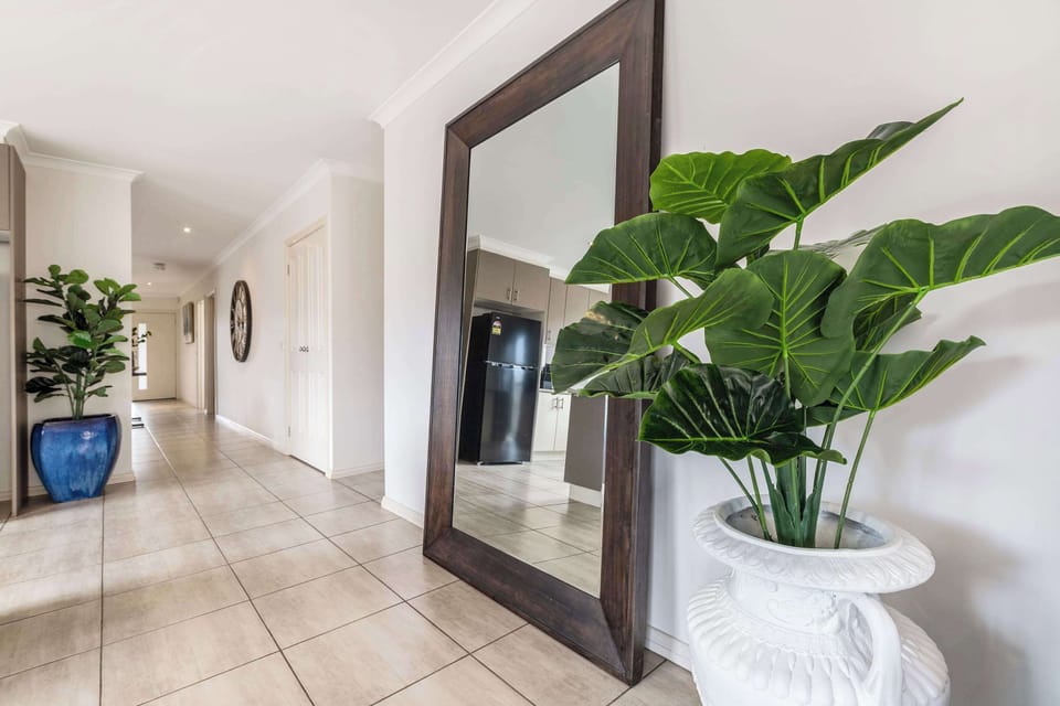 A welcoming hallway with modern décor, large mirror, and lush greenery to set a warm tone as you enter the home