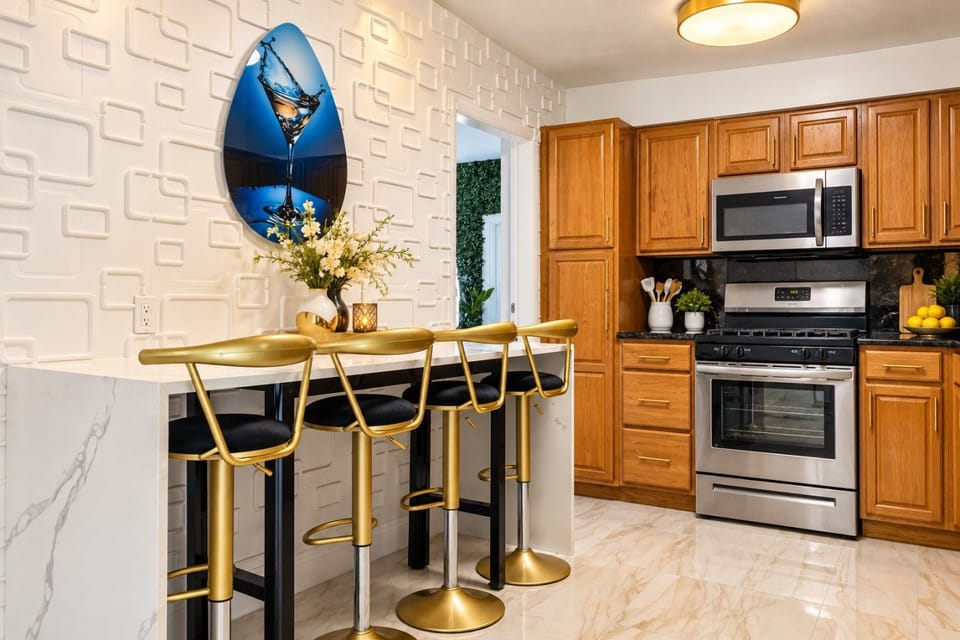 Stylish Kitchen with Breakfast Bar! Full appliances, granite counters & chic gold bar stools for 4. Modern textured accent wall & ocean artwork add flair. Perfect for morning coffee or quick meals. Hollywood Beach villa with games & hot tub nearby!