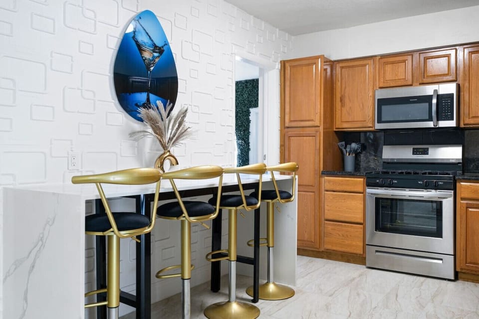 🍳 Stylish Kitchen with Breakfast Bar! Full appliances, granite counters & chic gold bar stools for 4. Modern textured accent wall & ocean artwork add flair. Perfect for morning coffee or quick meals. Hollywood Beach villa with games & hot tub nearby!