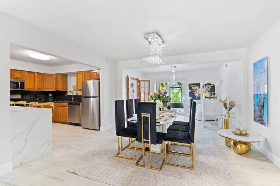 ✨ Stunning Open Concept Living! Kitchen, dining & lounge flow seamlessly with crystal chandelier, gold accents & modern design. Seats 8+ comfortably for entertaining. Hollywood Beach villa with game rooms, poker tables, hot tub & beach 3min away!