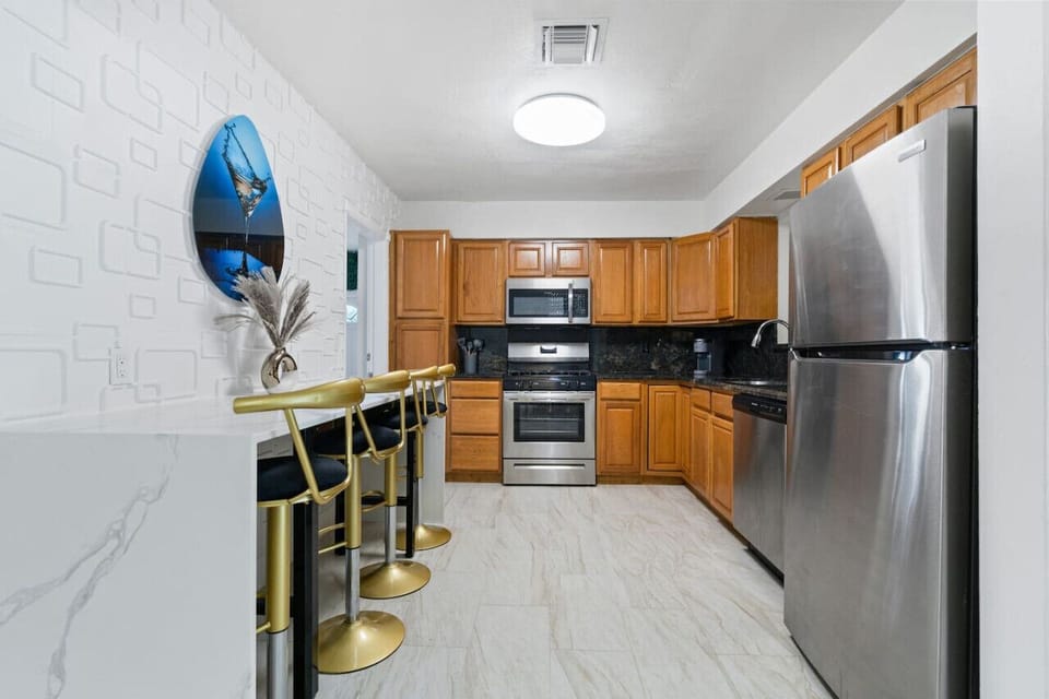 👨‍🍳 Fully Equipped Gourmet Kitchen! Stainless steel appliances, granite countertops & stylish gold bar seating for 4. Perfect for cooking family meals or entertaining guests. Part of Hollywood Beach villa with game rooms, hot tub & beach just 3min away!