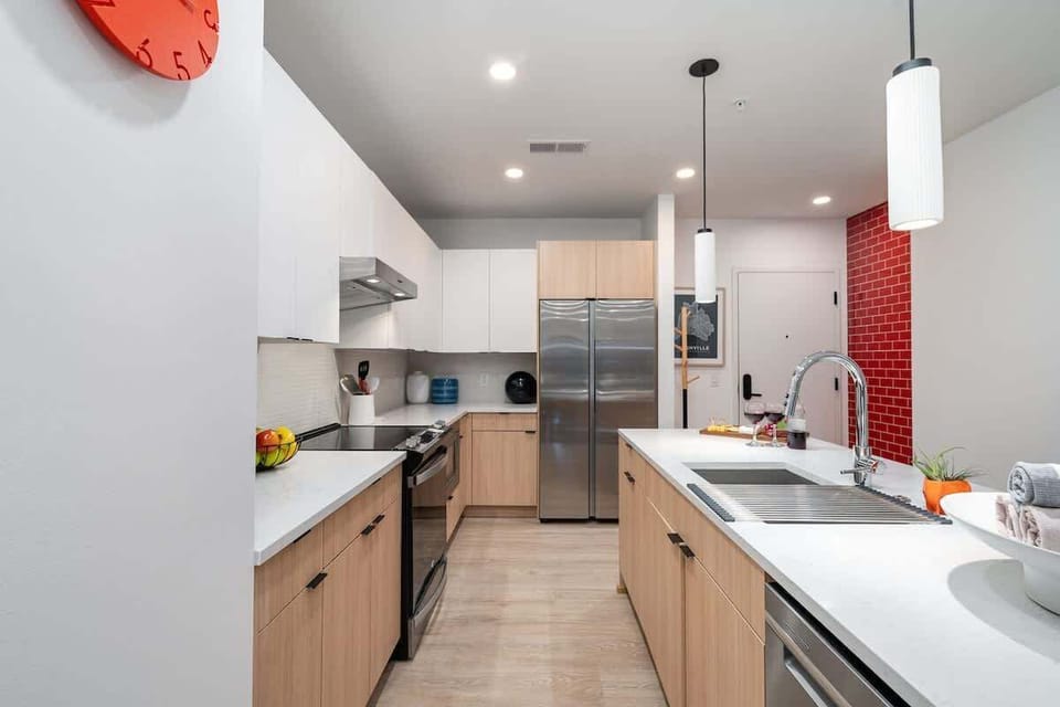 The fully equipped modern kitchen features culinary essentials, stainless steel appliances, and island bar seating.