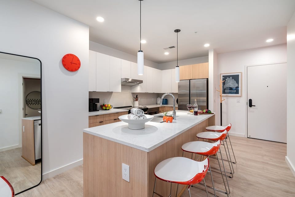 The fully equipped modern kitchen features culinary essentials, stainless steel appliances, and island bar seating.