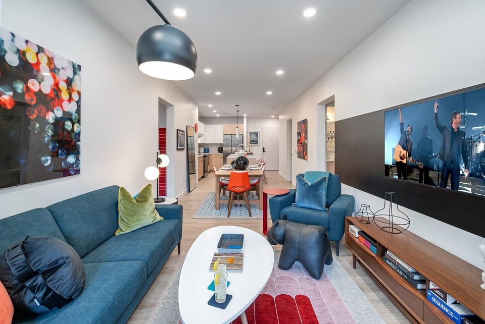 Bright open living space featuring a smart flat-screen TV, designer furnishings, and access to the outdoor patio.