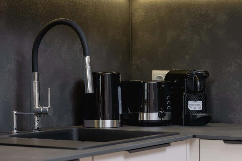 Close-up in the kitchen for a dark sink and a sleek tap and set for brewing coffee or tea.