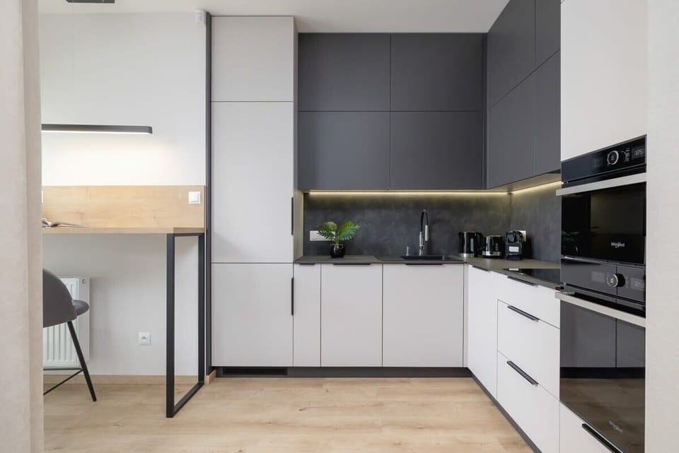 A sleek, modern kitchen with black and white cabinets, a built-in oven, and a minimalist design.