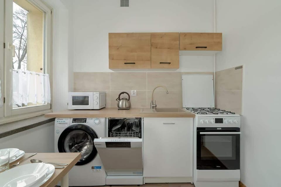 A kitchen view with wooden cabinets, a gas stove, and a window providing natural light, creating a well-lit and functional cooking area.


