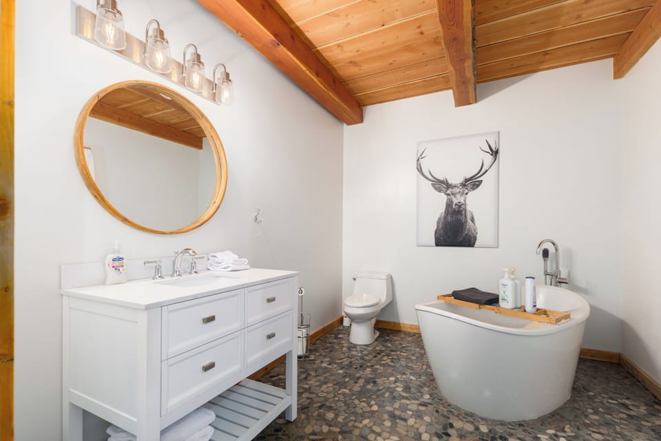 'Spa' bathroom with freestanding soaker tub, custom stone flooring, and warm wood ceiling