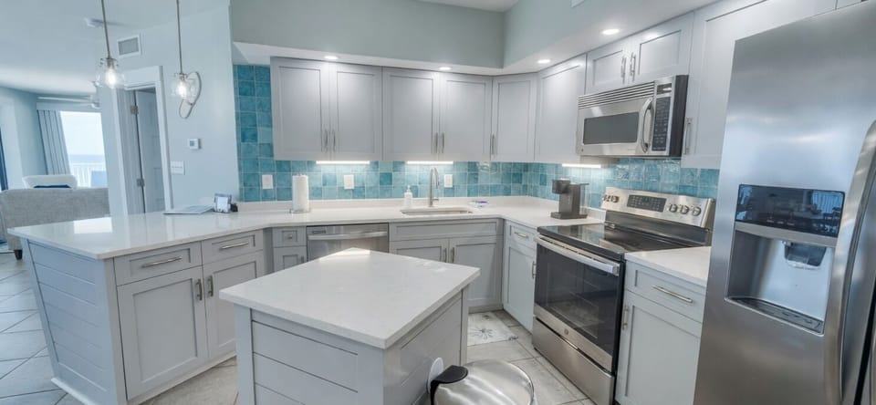 Bright coastal kitchen with island, quartz counters, and stainless appliances