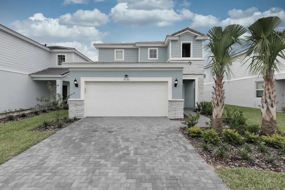 Stylish coastal home with modern charm, private driveway, and palm-lined entry.